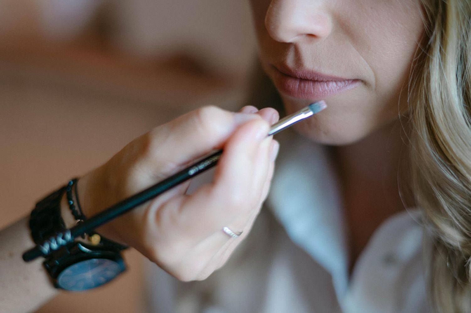 Close-up sequence showing someone applying pink lip gloss with a wand applicator.