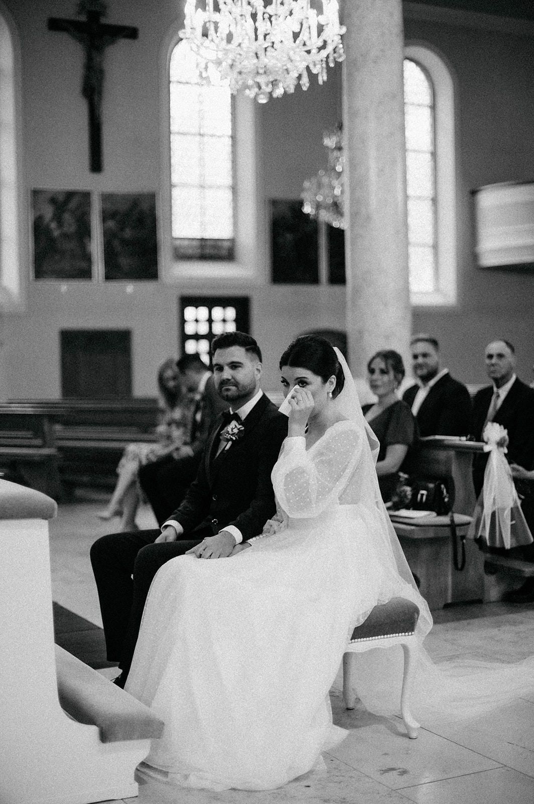 A black and white photo series of a bride and groom during their wedding ceremony in a traditional church setting.