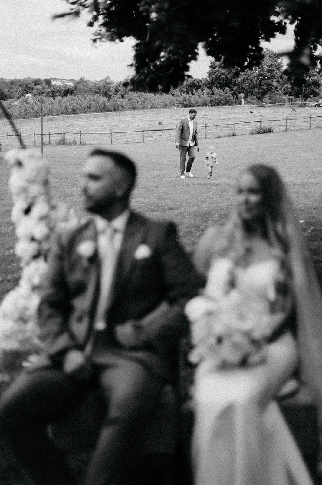 A series of black and white wedding photos showing couples in formal attire standing outdoors in a field.