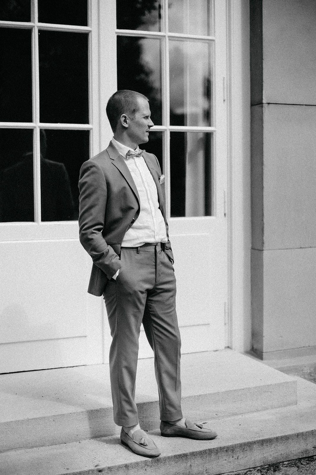 Black and white photo series showing a small child in formal attire leaning against a white building exterior.