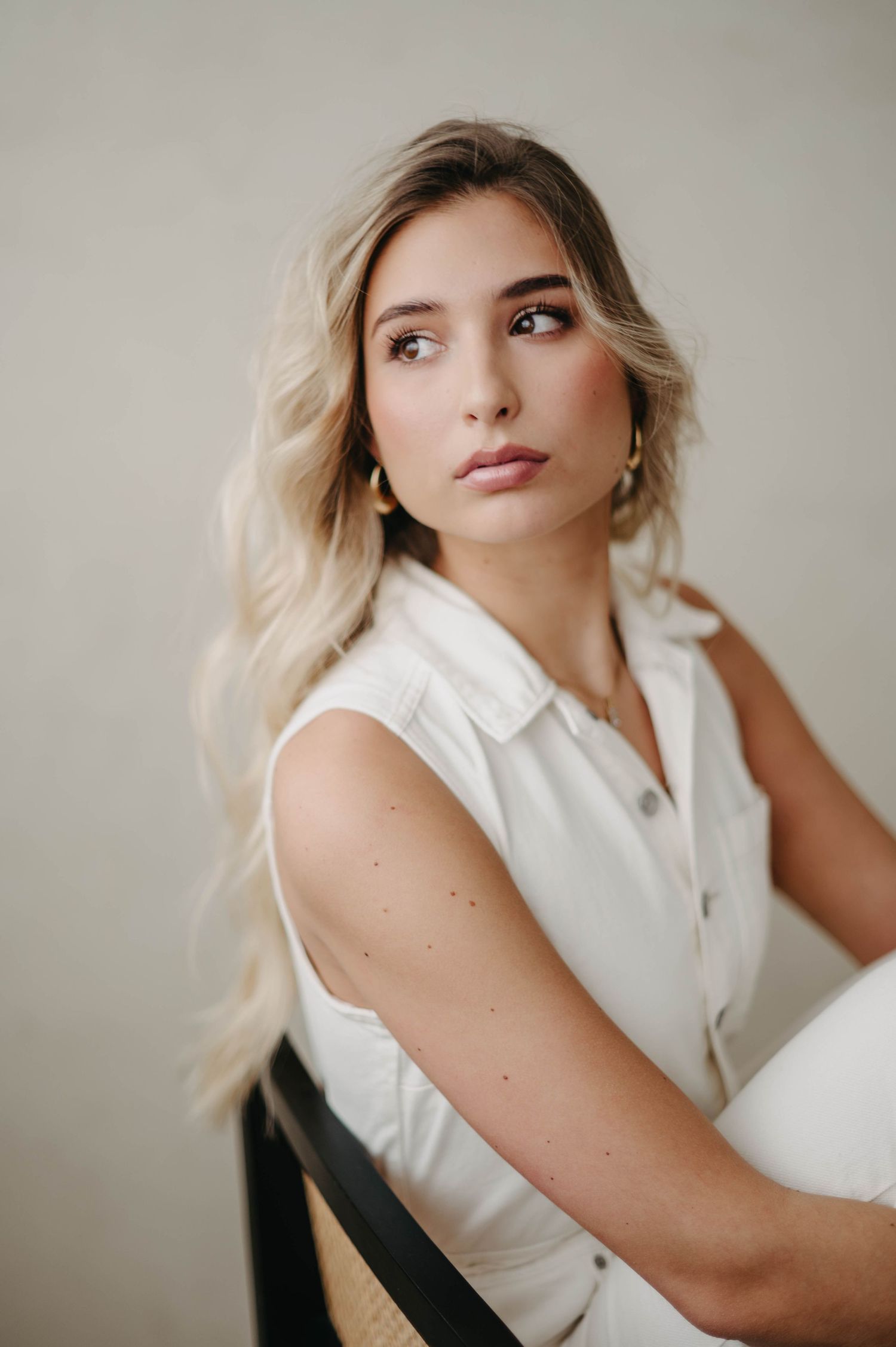 Fashion portrait featuring a white collared sleeveless top against a neutral background.