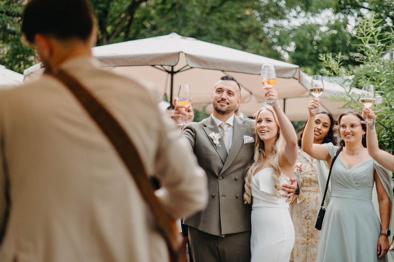 Wedding guests mingle under a white tent canopy during an outdoor celebration.