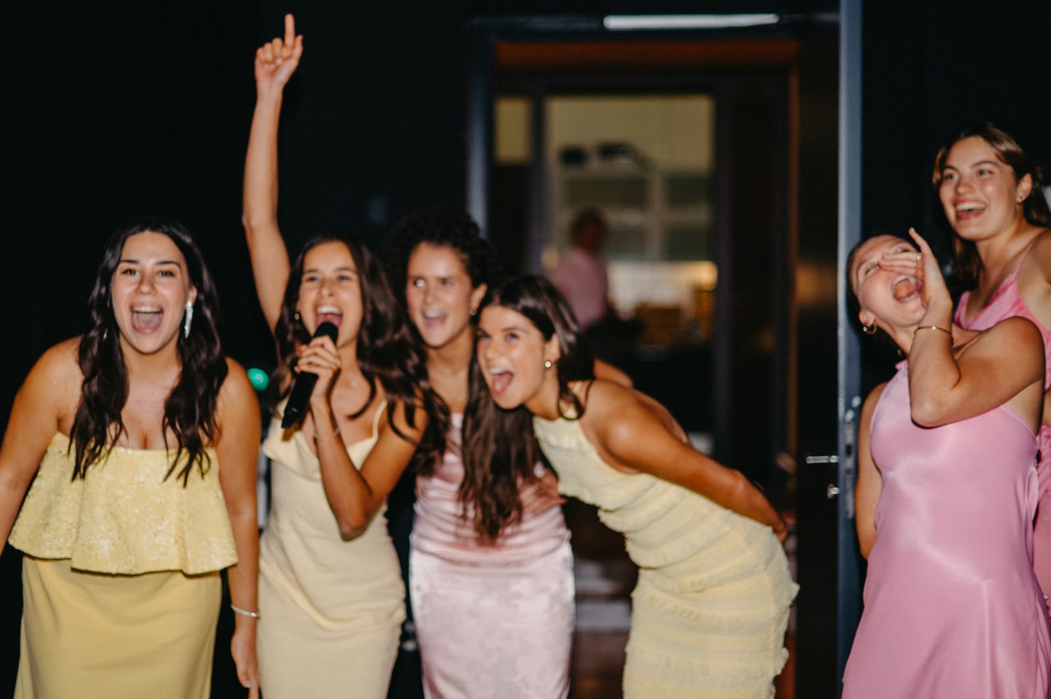 A group of people dancing and celebrating at a lively party with joyful expressions and raised arms.