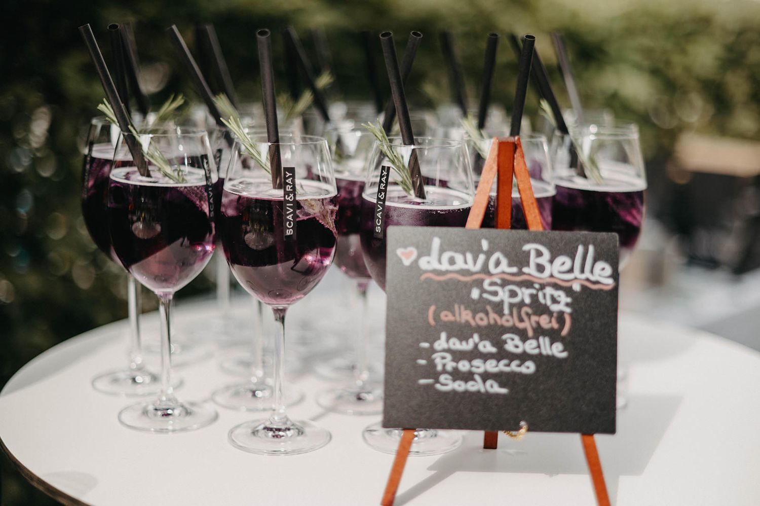 Wine glasses and chalkboard name cards arranged on a rustic wooden table at a wedding reception.