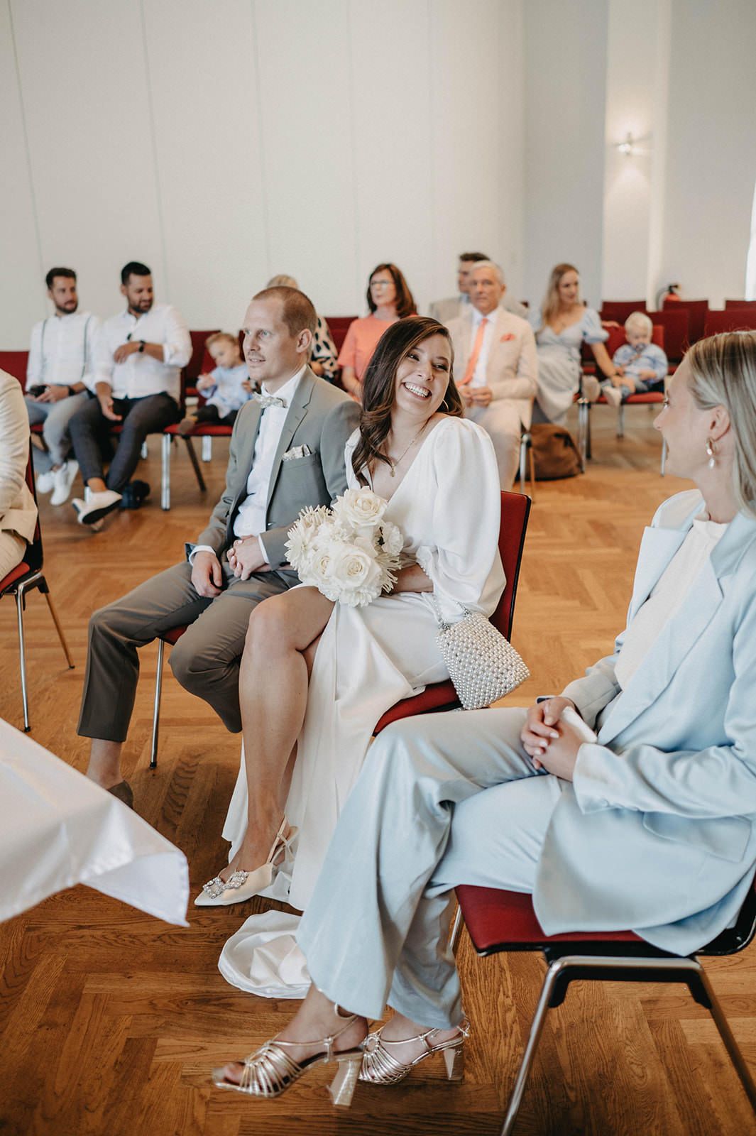 Wedding guests seated in rows of chairs during an indoor civil ceremony.