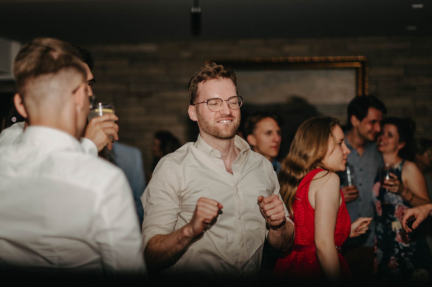 Wedding guests celebrate and dance together during an evening reception.