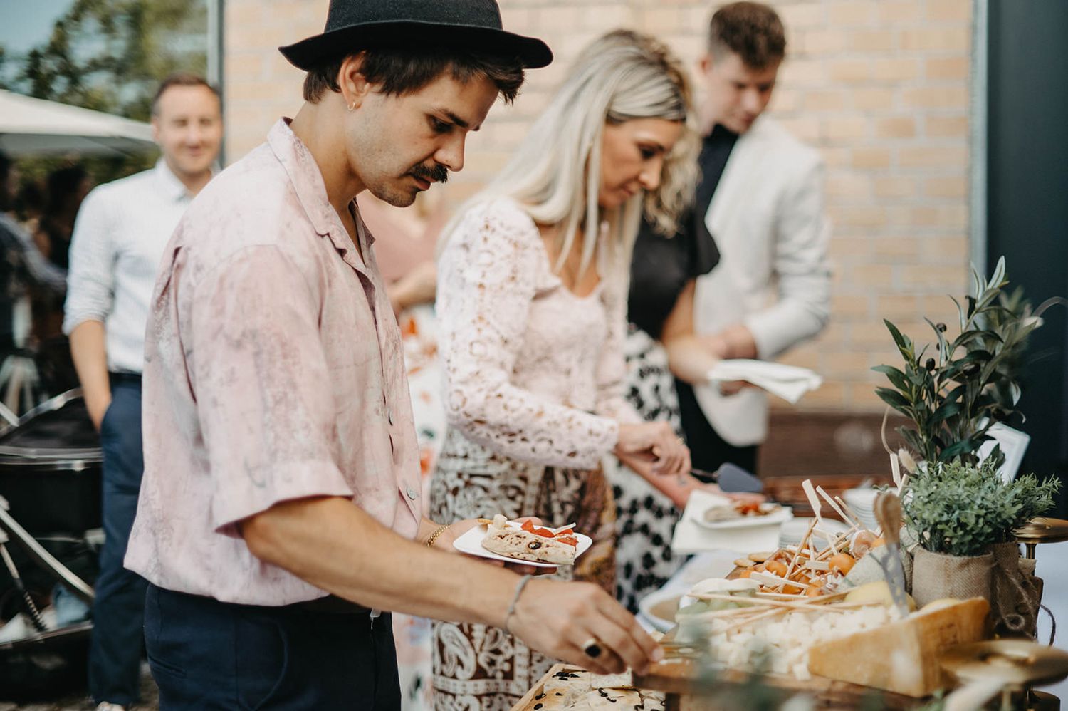 Guests serve themselves at an elegant buffet table with appetizers and small plates at a catered event.