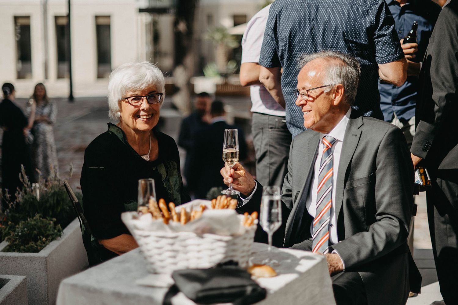 Group of people in business attire gathered for a social event with drinks and conversation.