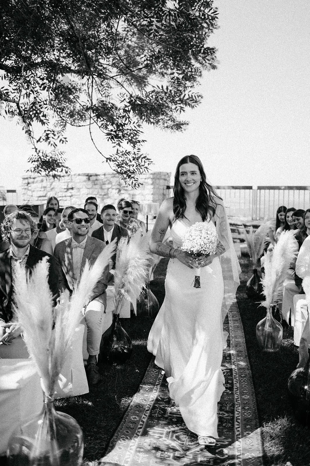 A sequence of black and white photos showing people in white clothing dancing and celebrating outdoors at a joyful event.