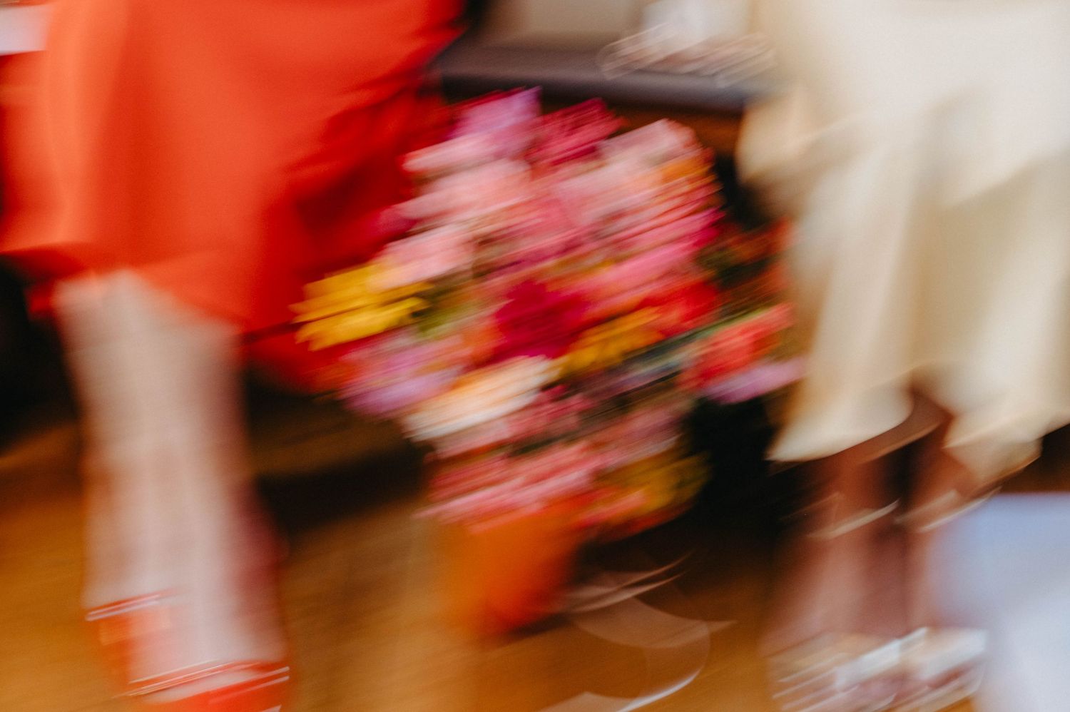 Blurred motion of performers in red costumes moving dynamically across a stage during a dance performance.
