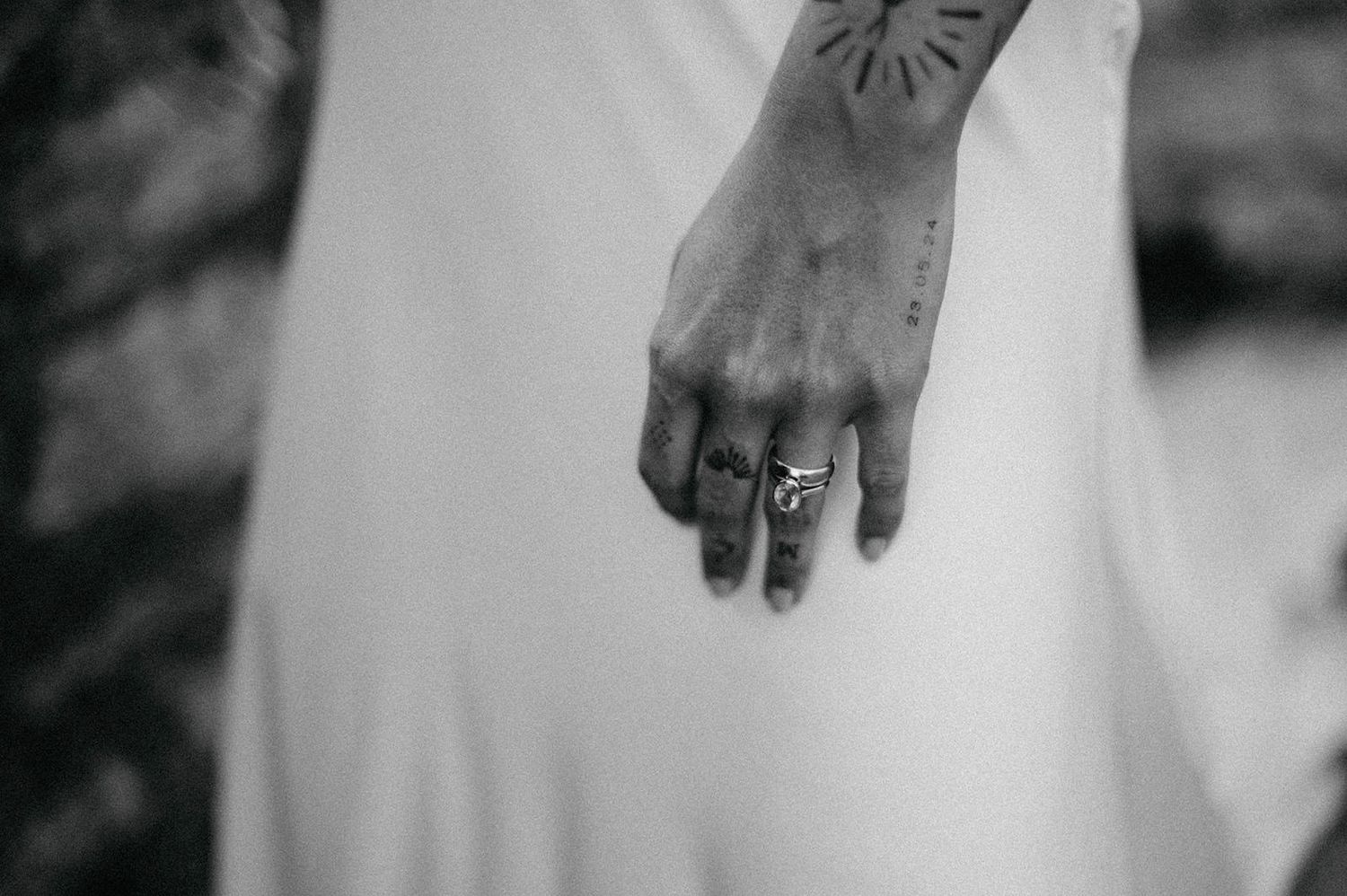 A close-up view of wedding rings and hands against a white background with soft lighting.