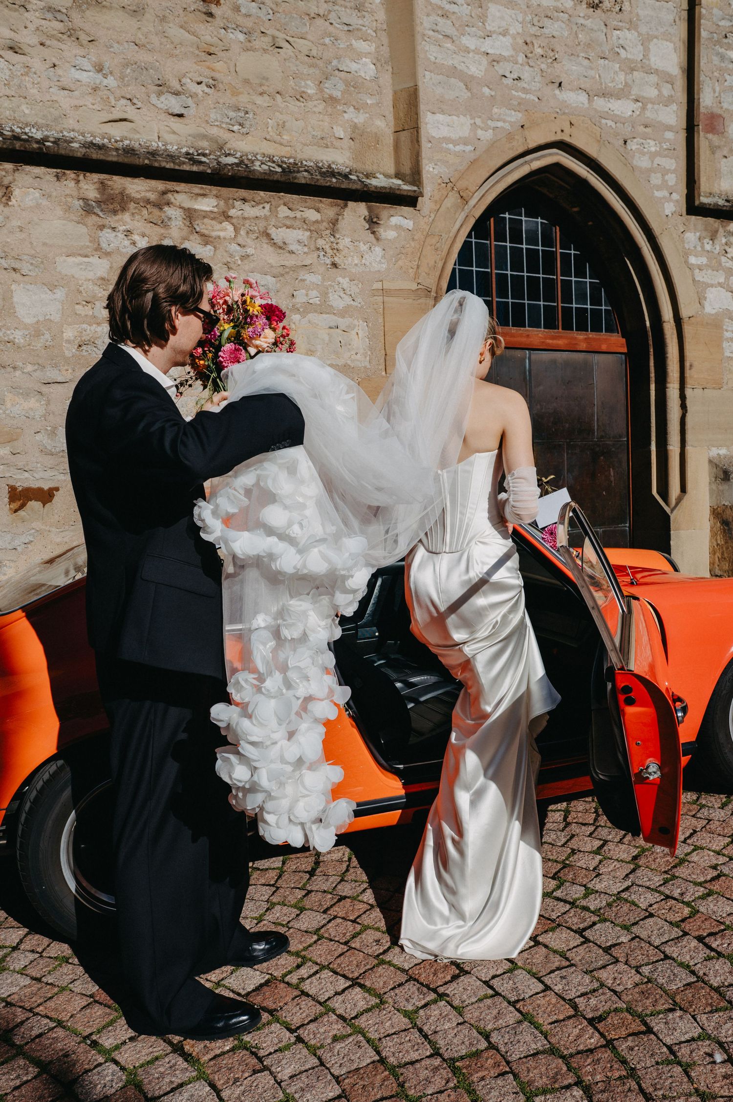 A sequence of romantic dance moves between a couple in formal wedding attire on a cobblestone courtyard.