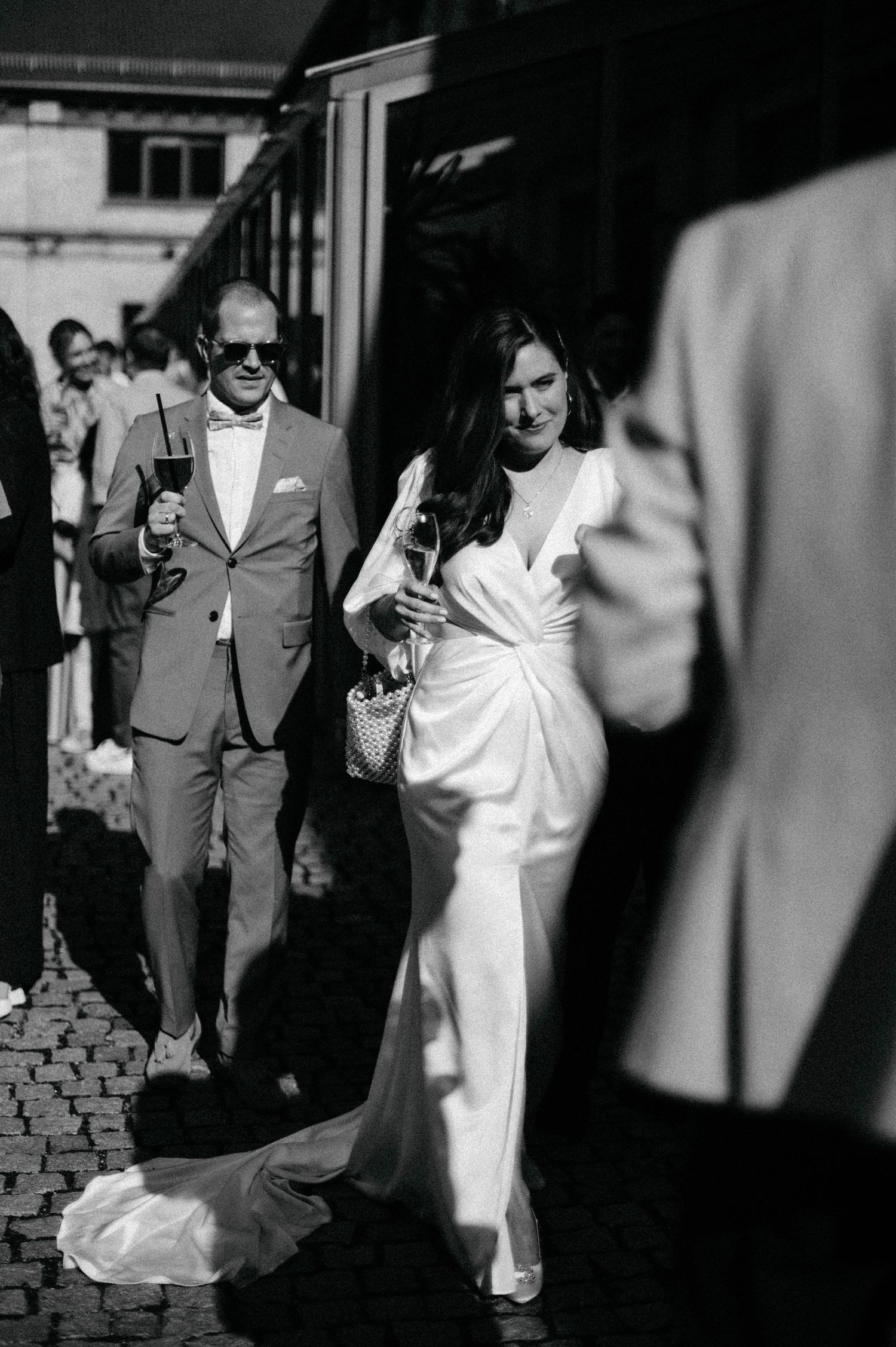 Black and white wedding photos with dramatic shadows on cobblestone path.