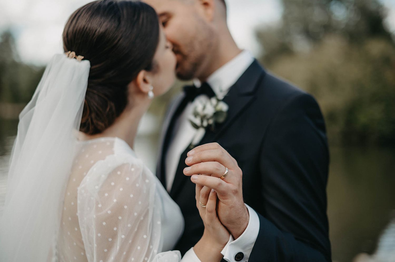 A couple shares an intimate moment during their outdoor wedding ceremony, with soft natural lighting.