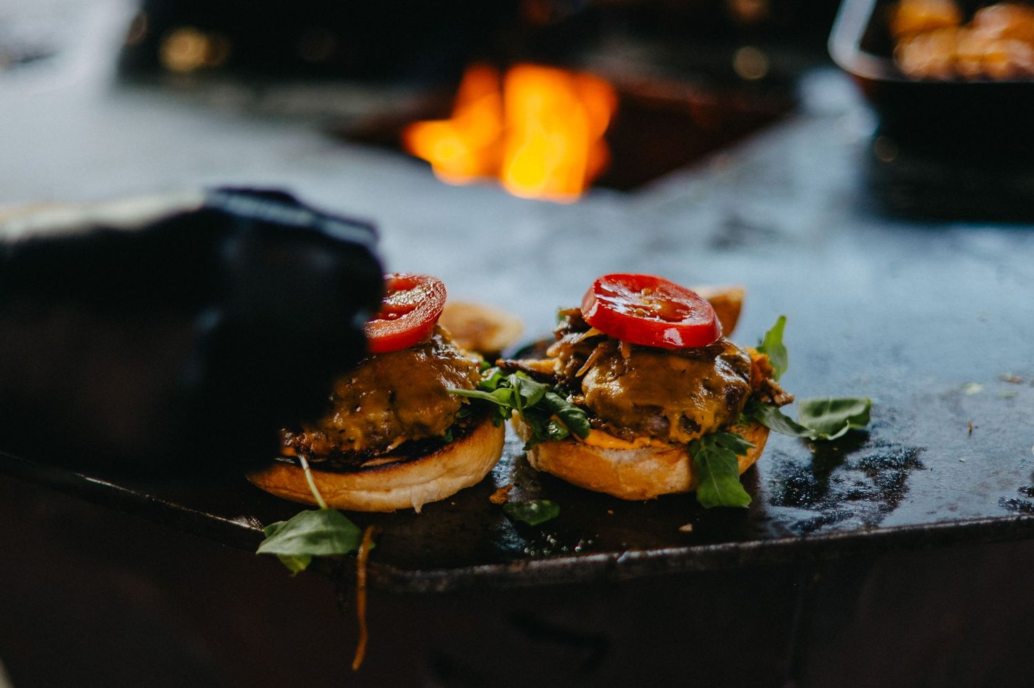 A series of small appetizers or canapés with colorful toppings arranged on dark plates in a restaurant setting.