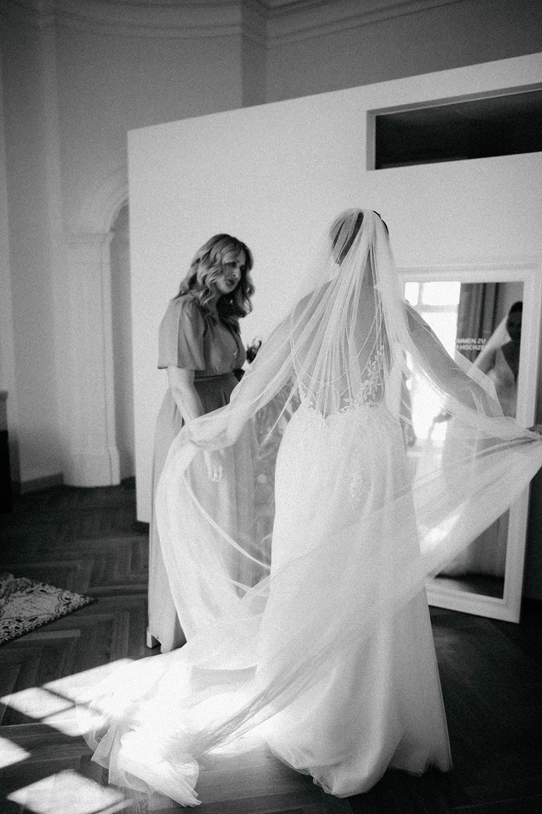 A series of black and white photos showing a flowing white wedding dress and veil in motion against an interior space.
