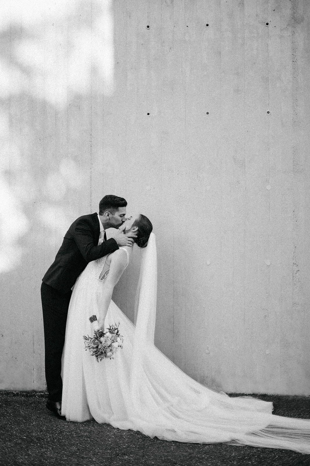 A romantic black and white wedding photo sequence showing a couple in formal attire sharing an intimate moment against a wall.
