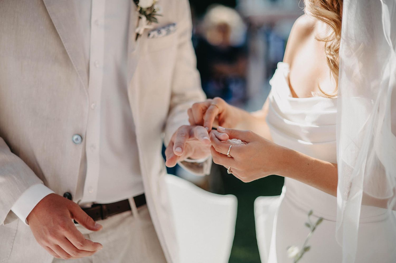 Bride and groom hold hands during a wedding ceremony while exchanging rings.
