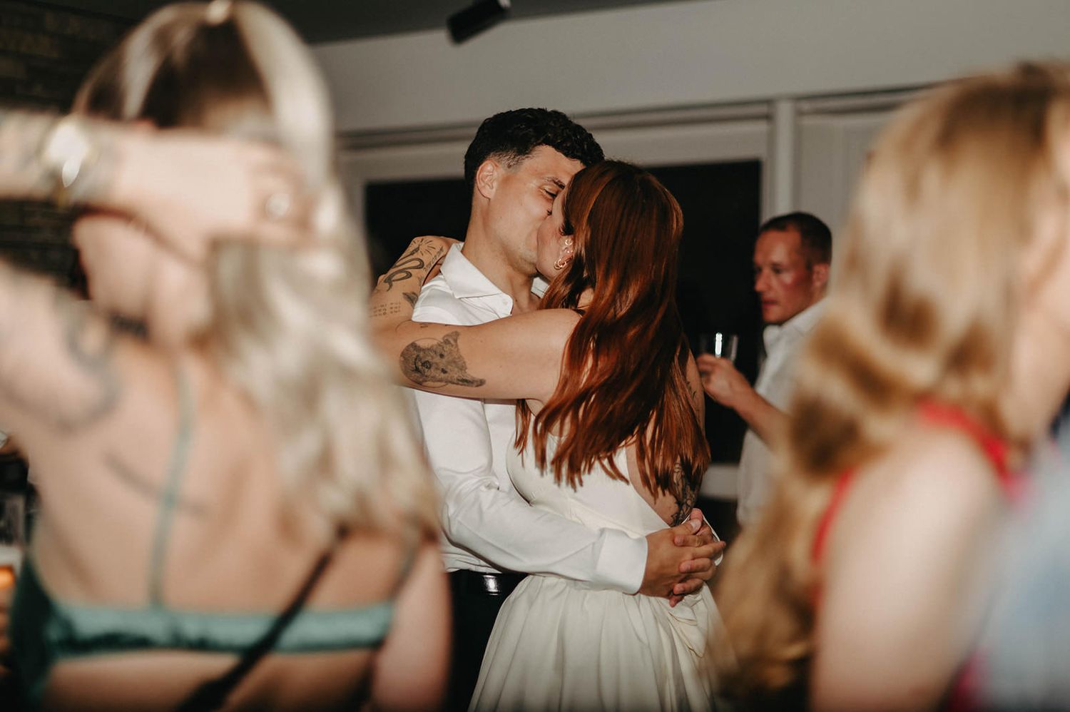 A couple shares an intimate dance moment at a wedding reception while other guests dance around them.