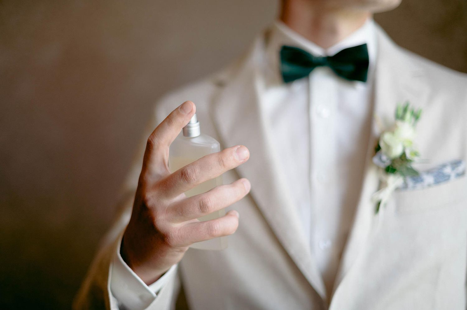 A close-up view of a black bow tie being adjusted on a crisp white dress shirt.
