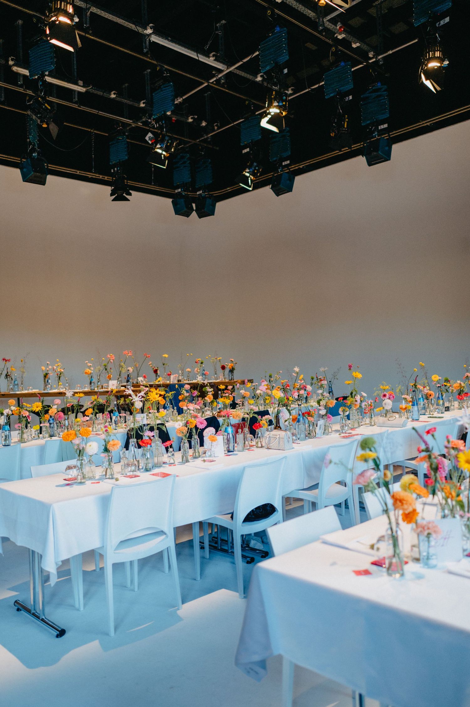 Long white tables display a colorful collection of toys and figurines under stage lighting in a modern exhibition space.