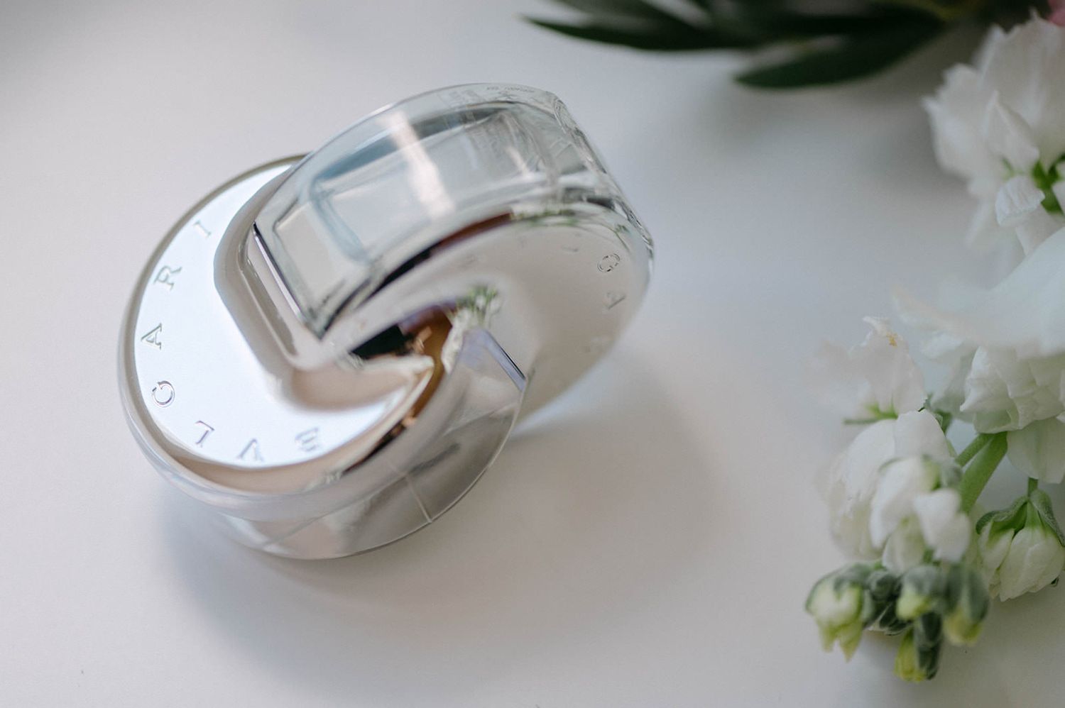 White flowers and silver wristwatches arranged on a light surface in a minimalist composition.