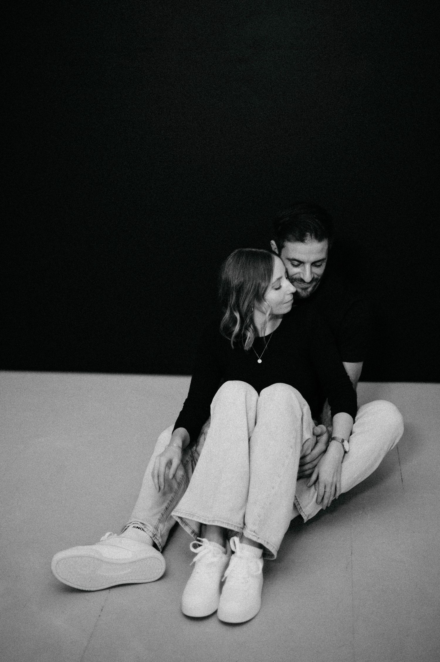 A candid black and white photo showing a tender moment between two people sitting on the floor.
