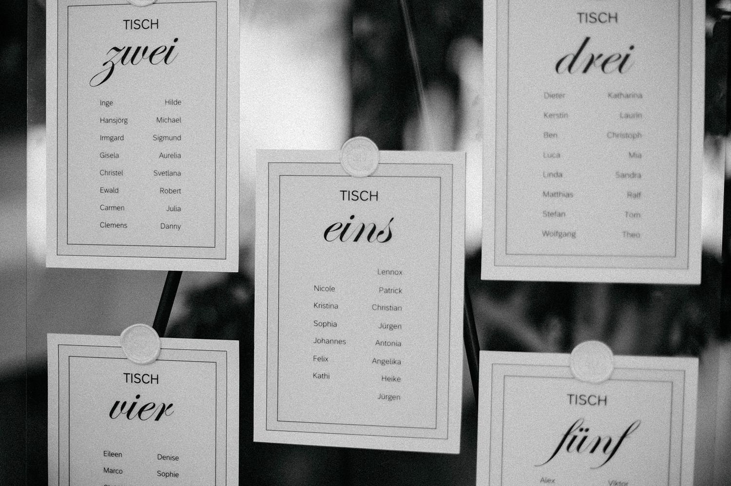 A series of elegant table number cards displayed in black and white frames for a formal event.