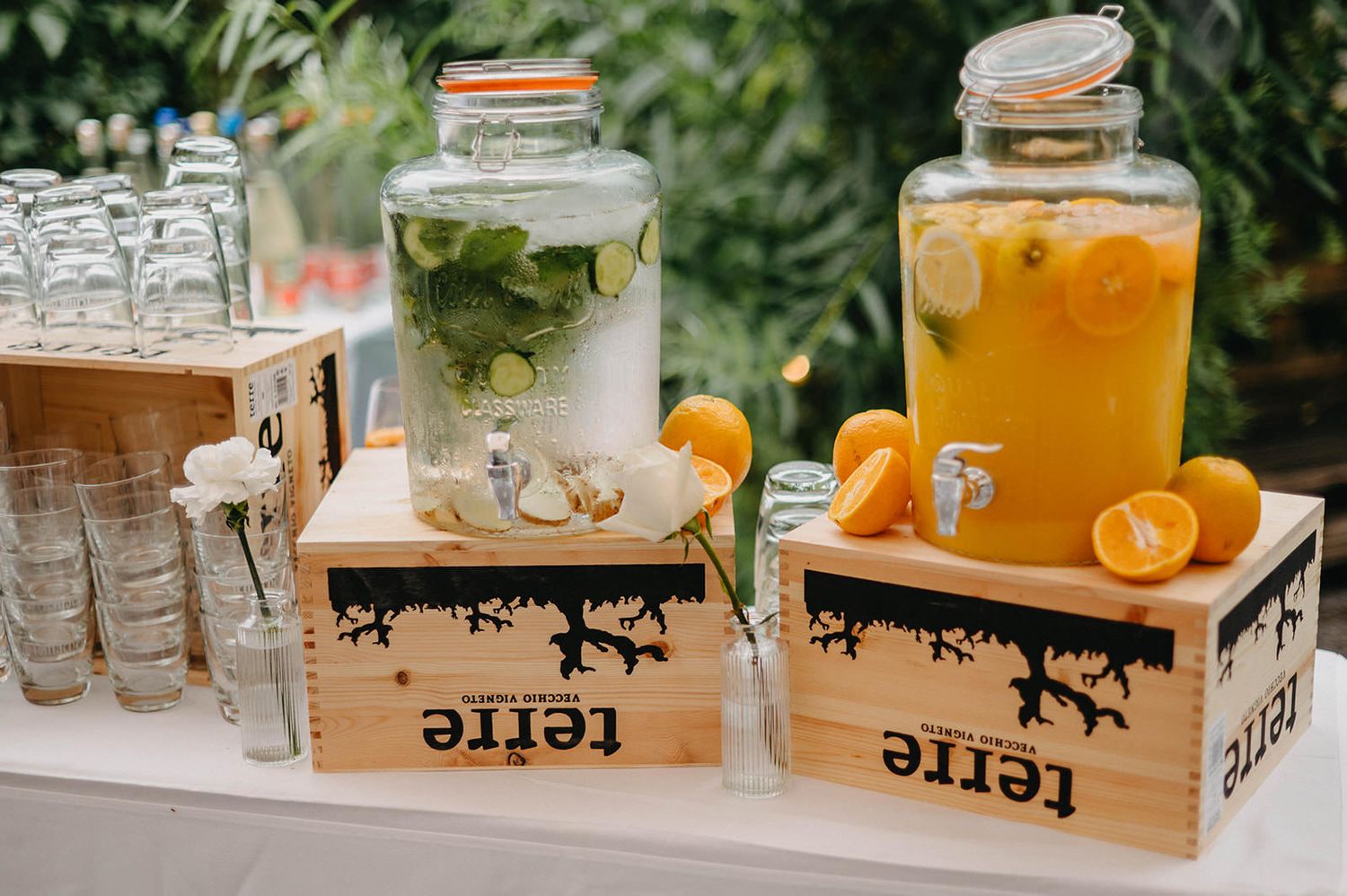 Rustic beverage station with glass drink dispensers filled with citrus-infused beverages on wooden crates.