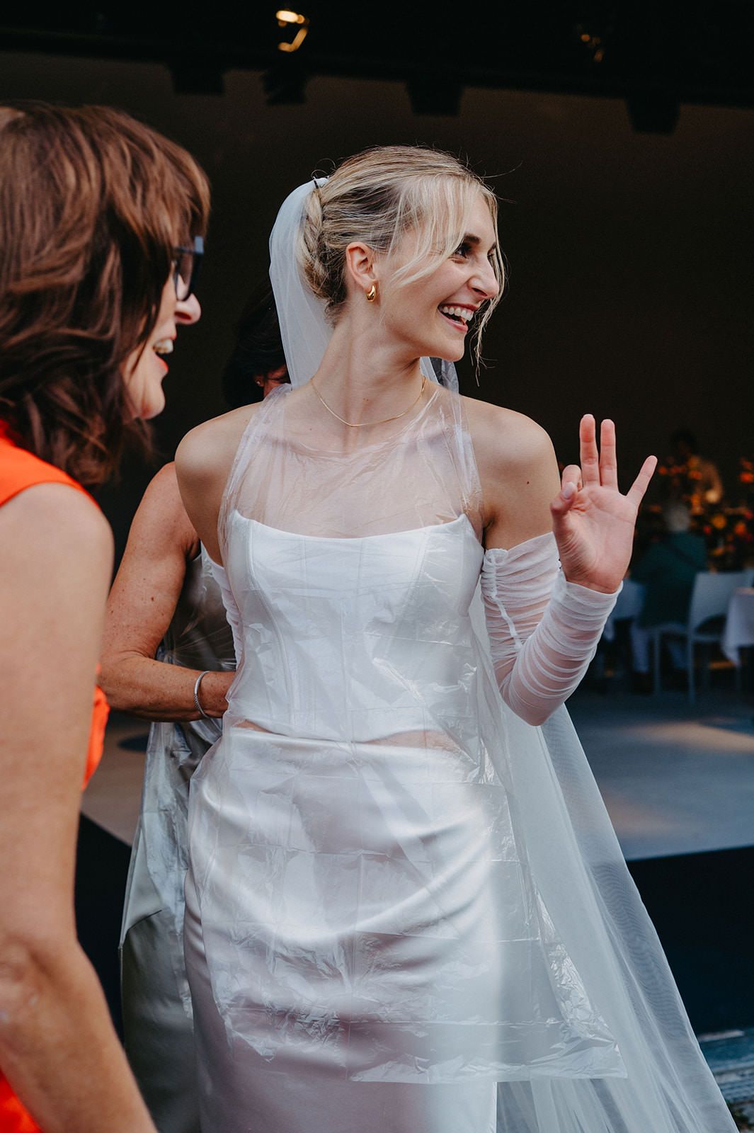 A bride in a white wedding dress laughs joyfully during a candid moment at her wedding celebration.