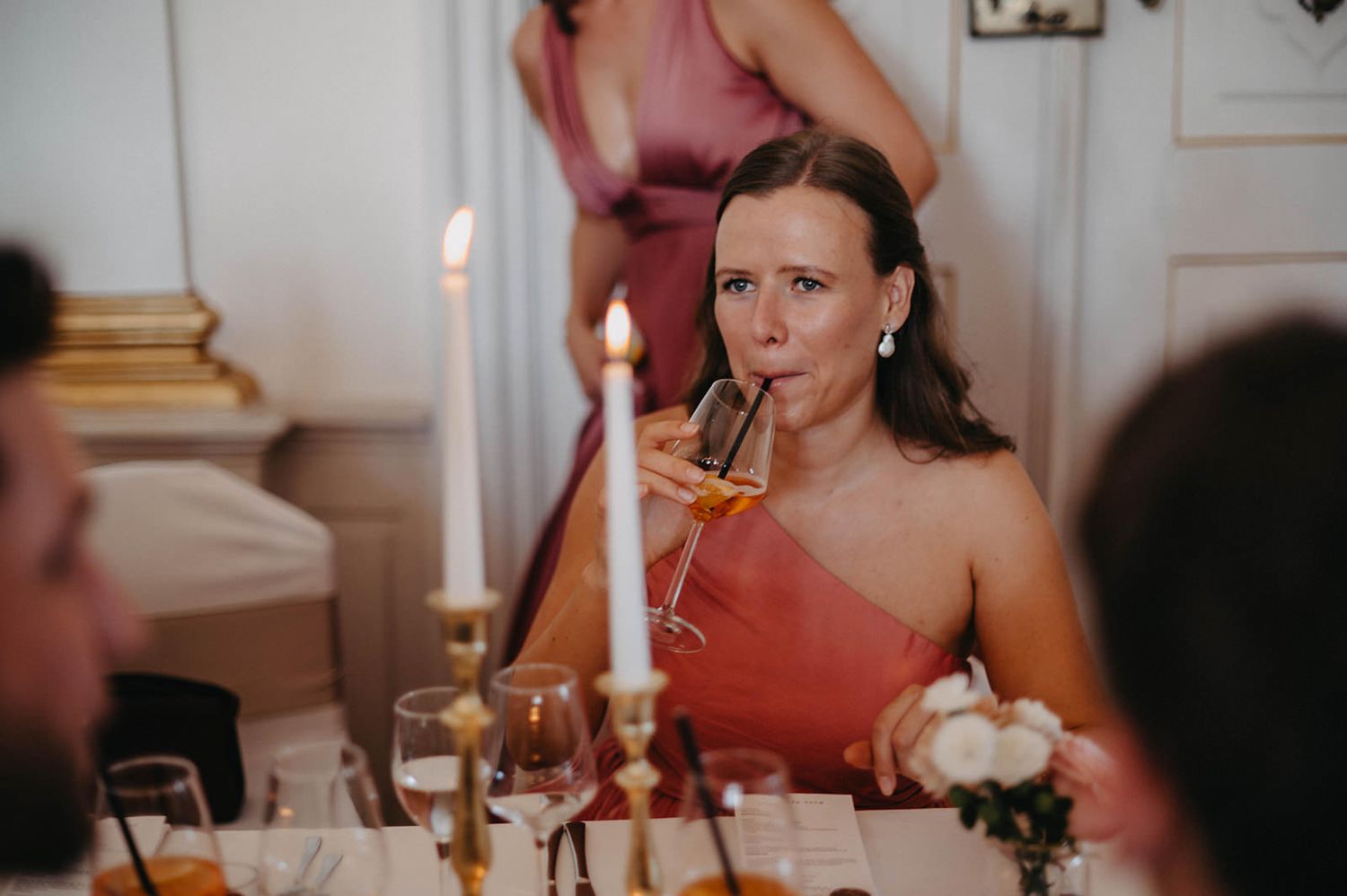 Candlelit dinner party table setting with elegant glassware and guests enjoying an intimate evening celebration.