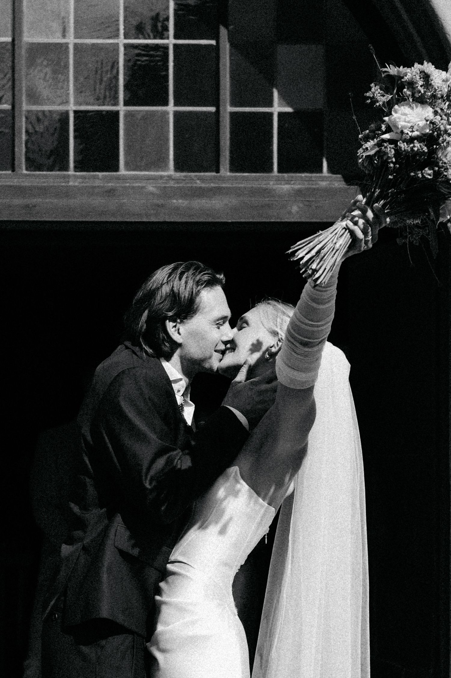 Black and white photo sequence showing a couple sharing a romantic kiss at their wedding ceremony.