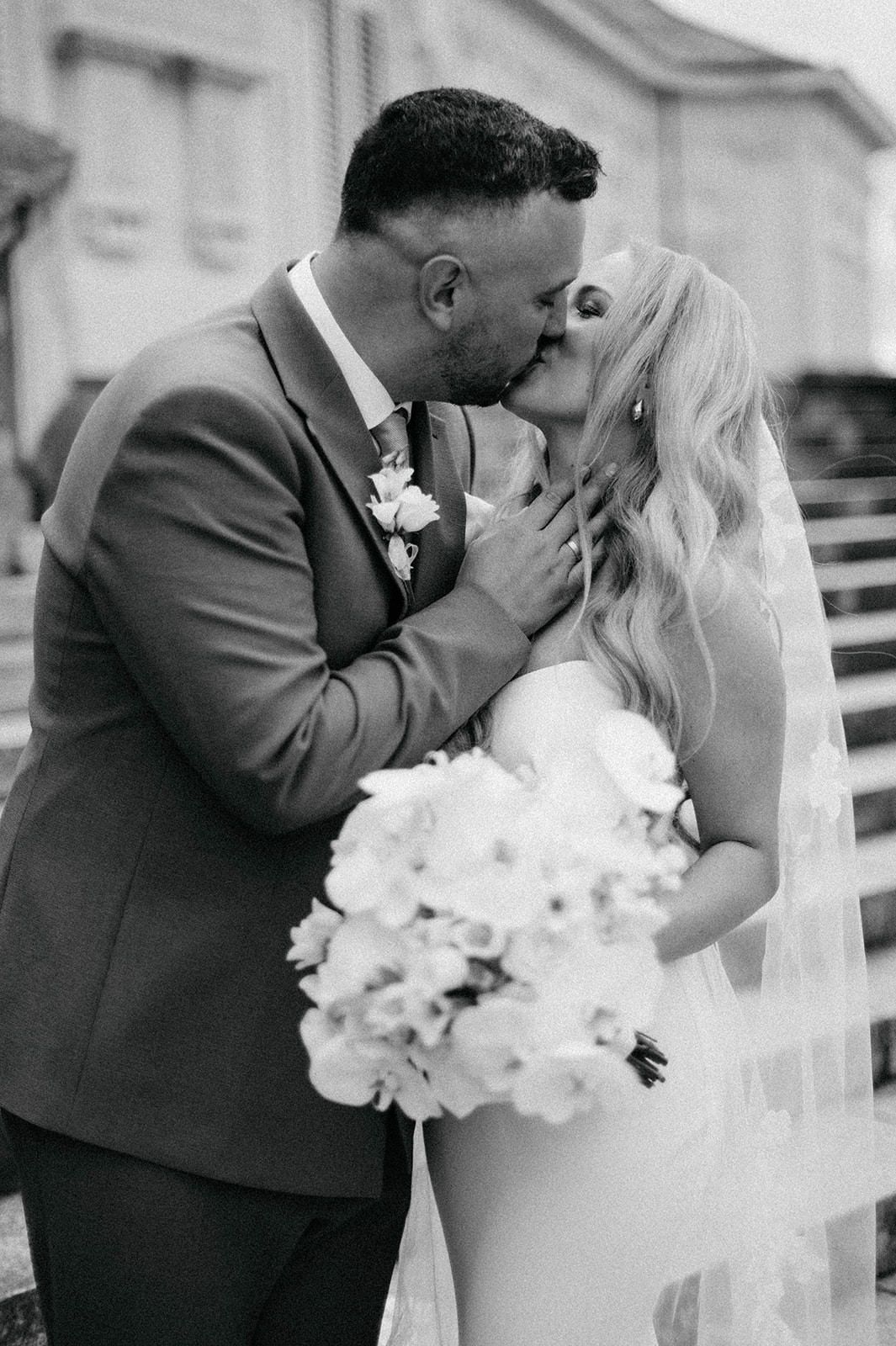 A romantic black and white photo sequence of newlyweds sharing their first kiss as a married couple.