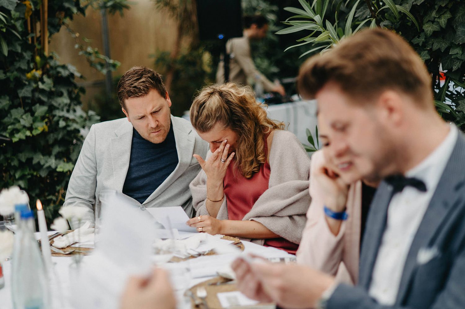 People sitting at tables outdoors signing papers and documents at an elegant event.