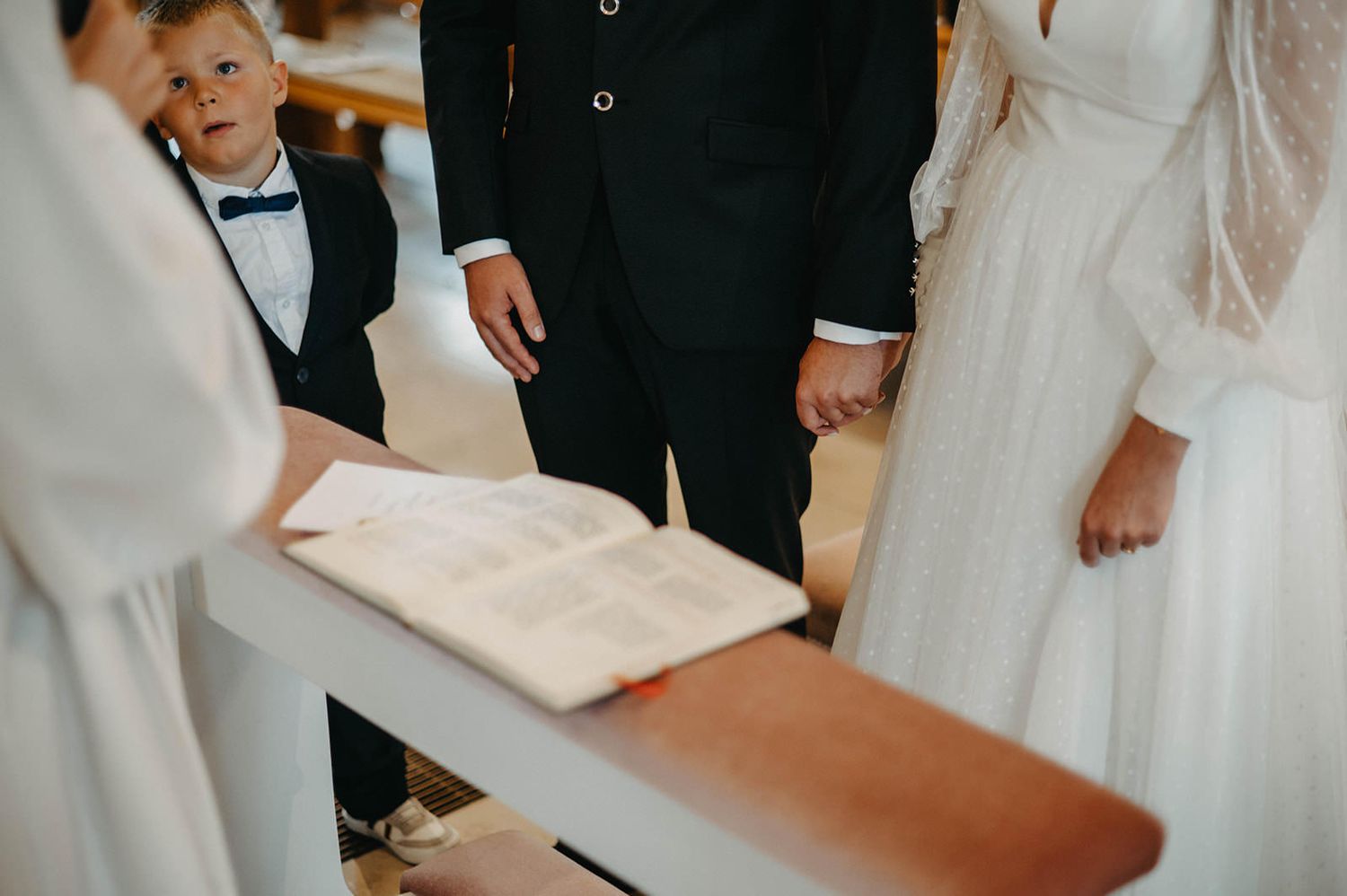 Close-up view of open prayer book during wedding ceremony with attendees gathered around.