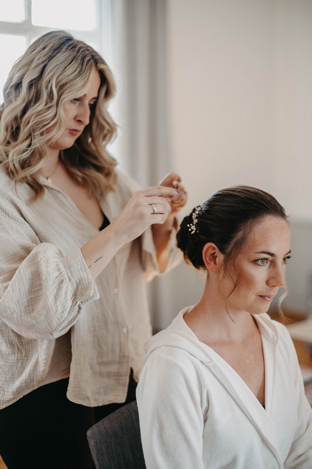 Getting ready scene with soft natural light as wedding preparations take place in a bright room.
