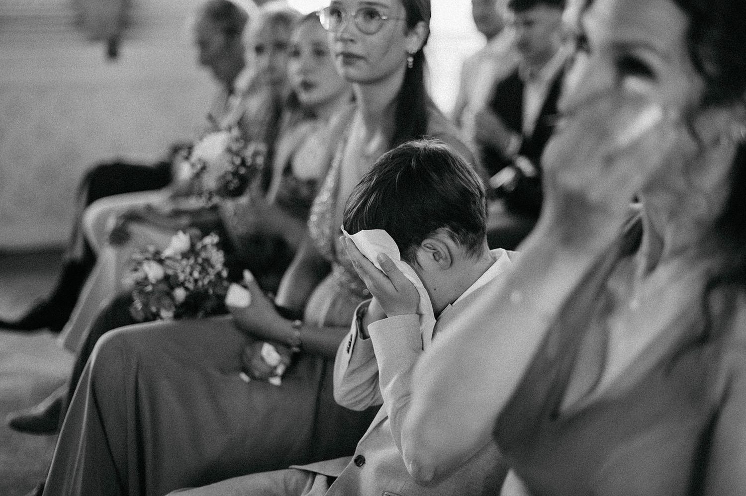 A black and white collage of audience members laughing and showing emotional reactions during a performance.