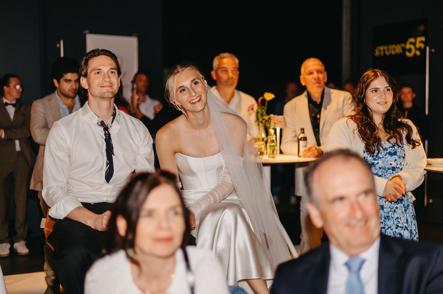 Wedding guests laugh and enjoy themselves during a reception celebration at an evening event.
