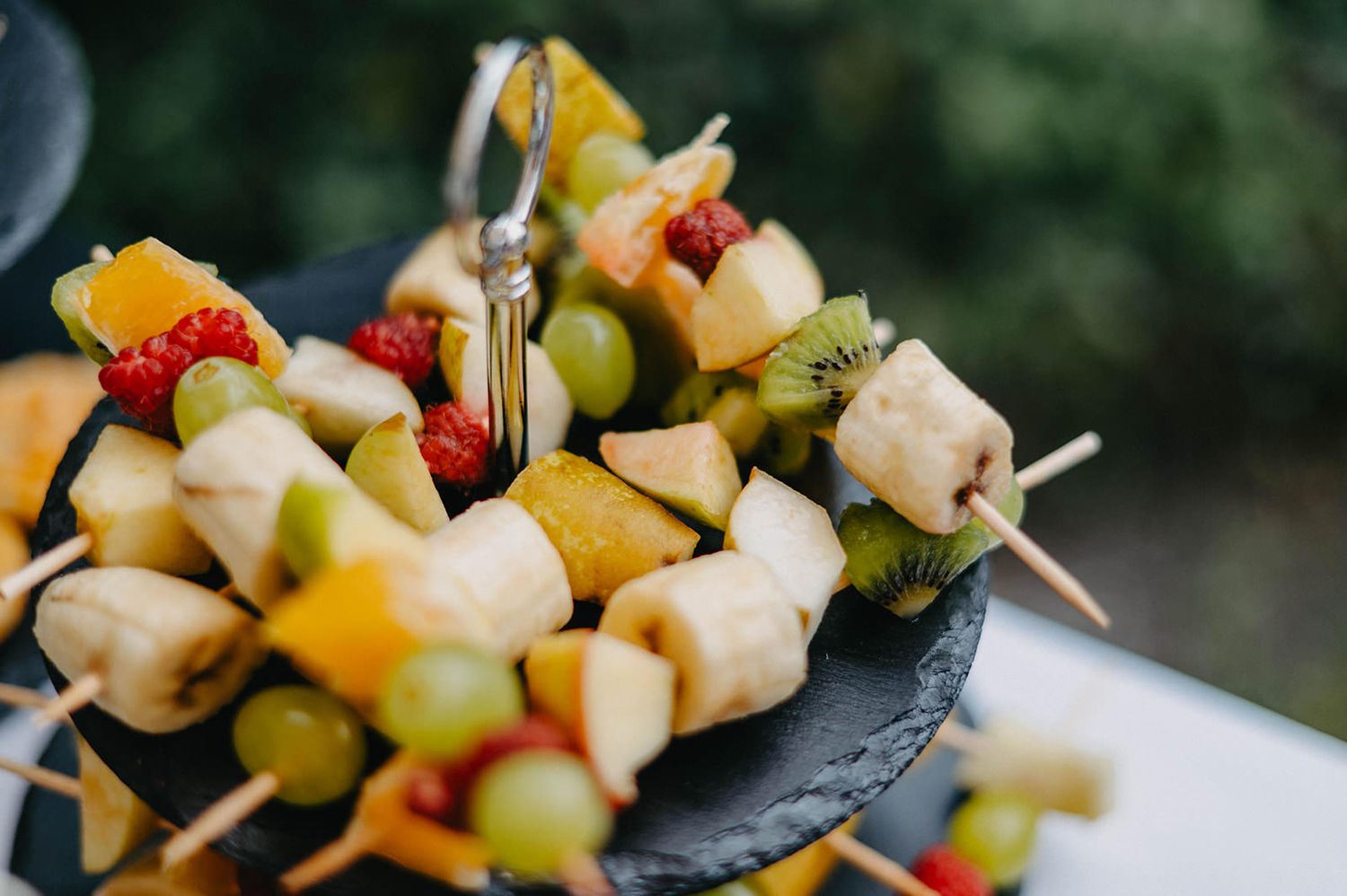 Colorful fruit and cheese appetizer skewers arranged in rows on a dark serving platter.