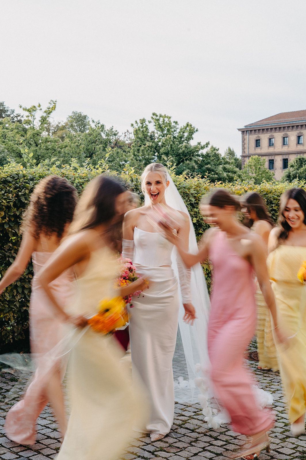 Bride in white gown with bridesmaids in pastel dresses creating motion blur effect.