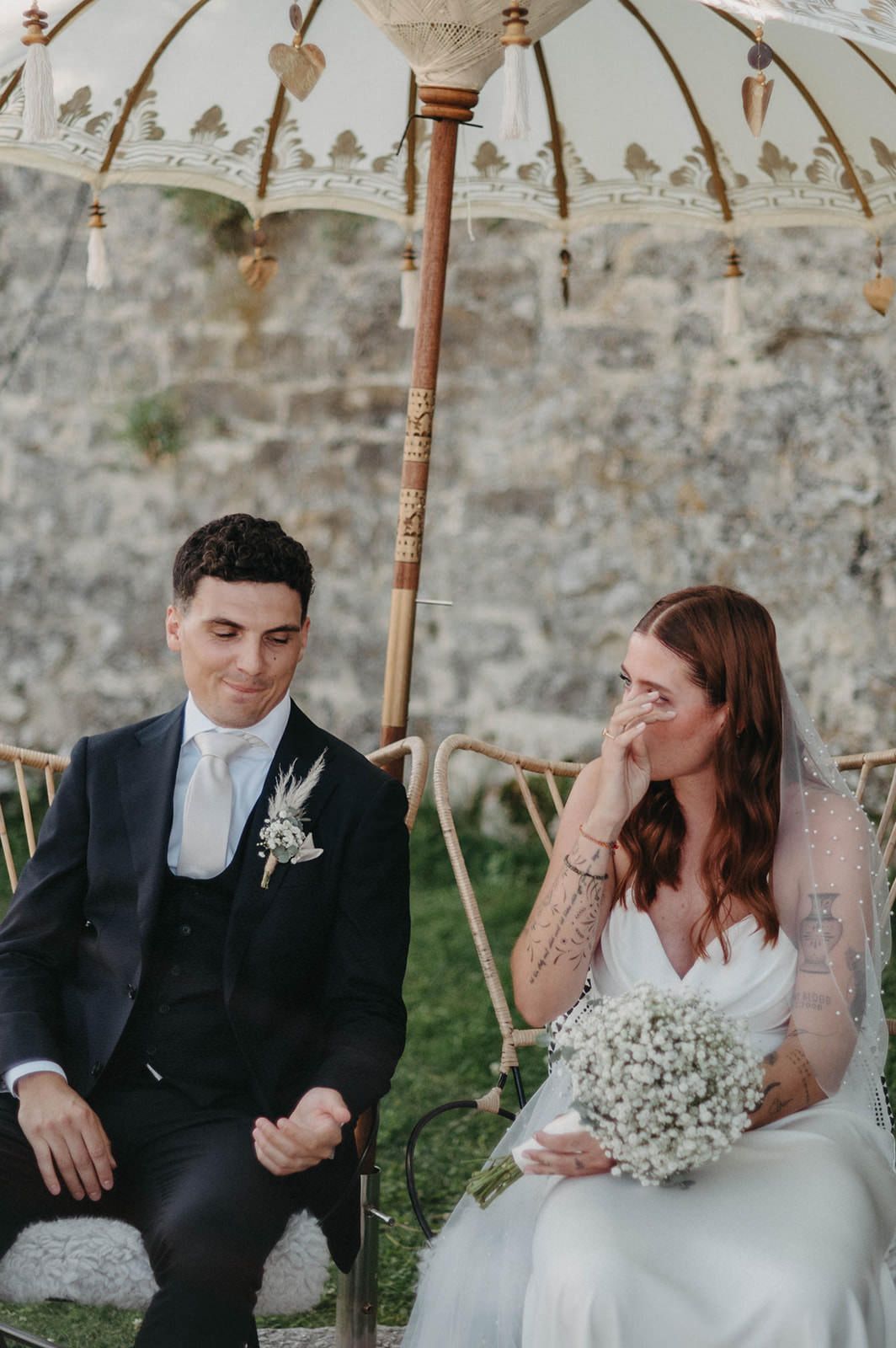 A couple shares intimate moments during their wedding ceremony under decorative hanging lights and umbrellas.