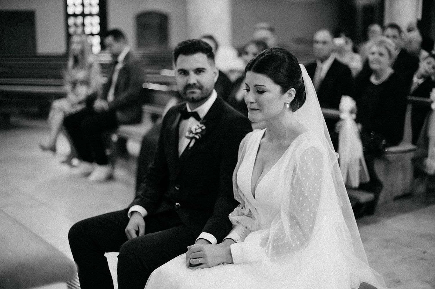 A series of black and white wedding ceremony photos showing emotional moments between couples in a church setting.