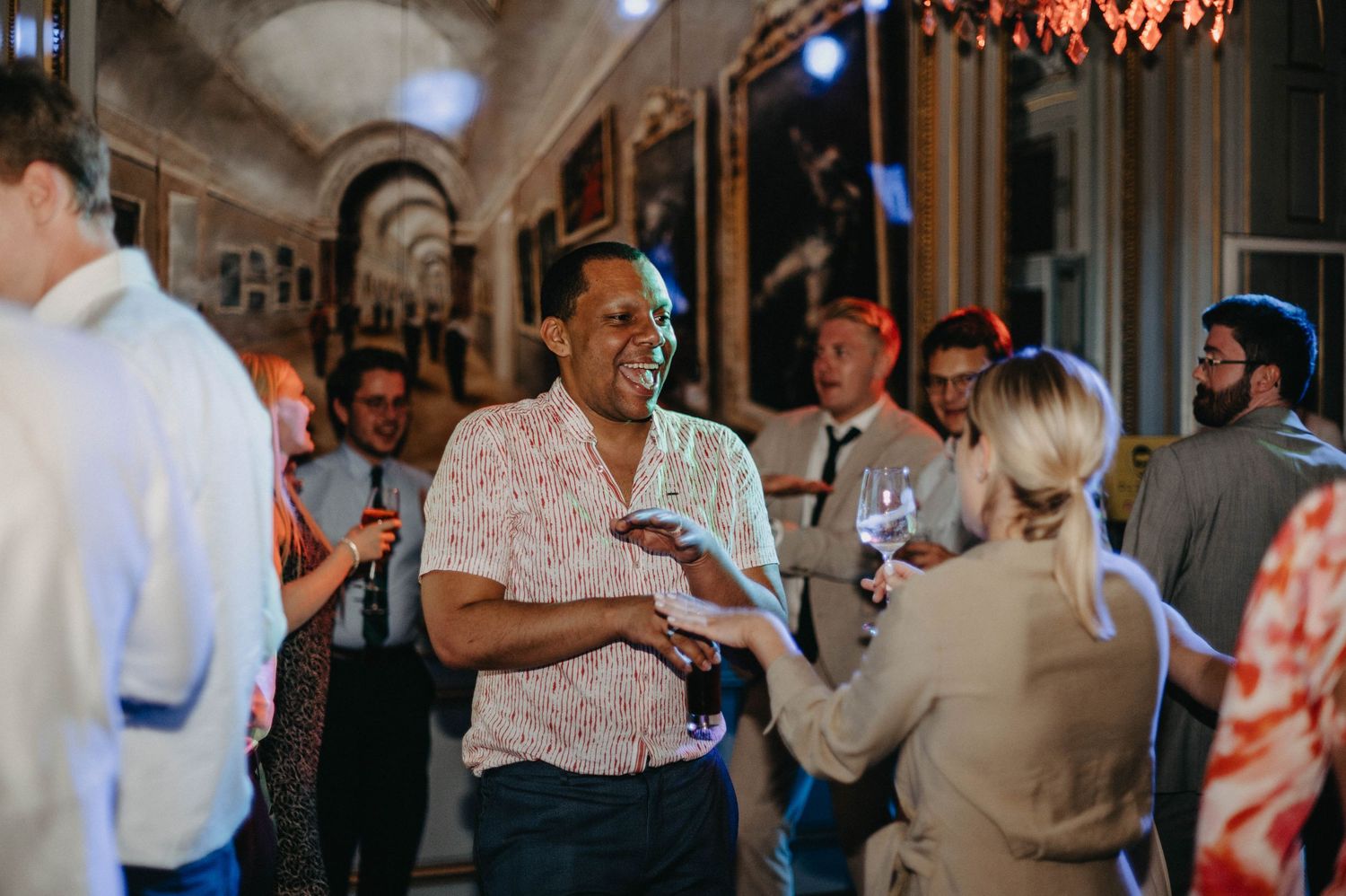 Elegant wedding reception with guests dancing and mingling in an ornate ballroom setting.