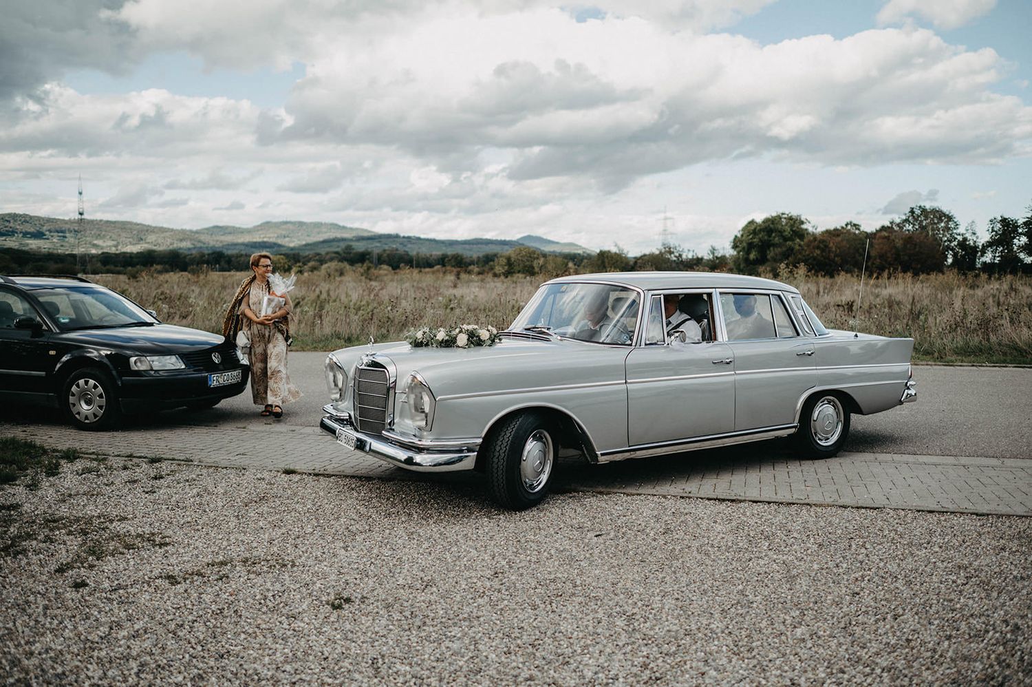 A panoramic sequence of vintage luxury cars parked in a desert landscape with mountains in the background.