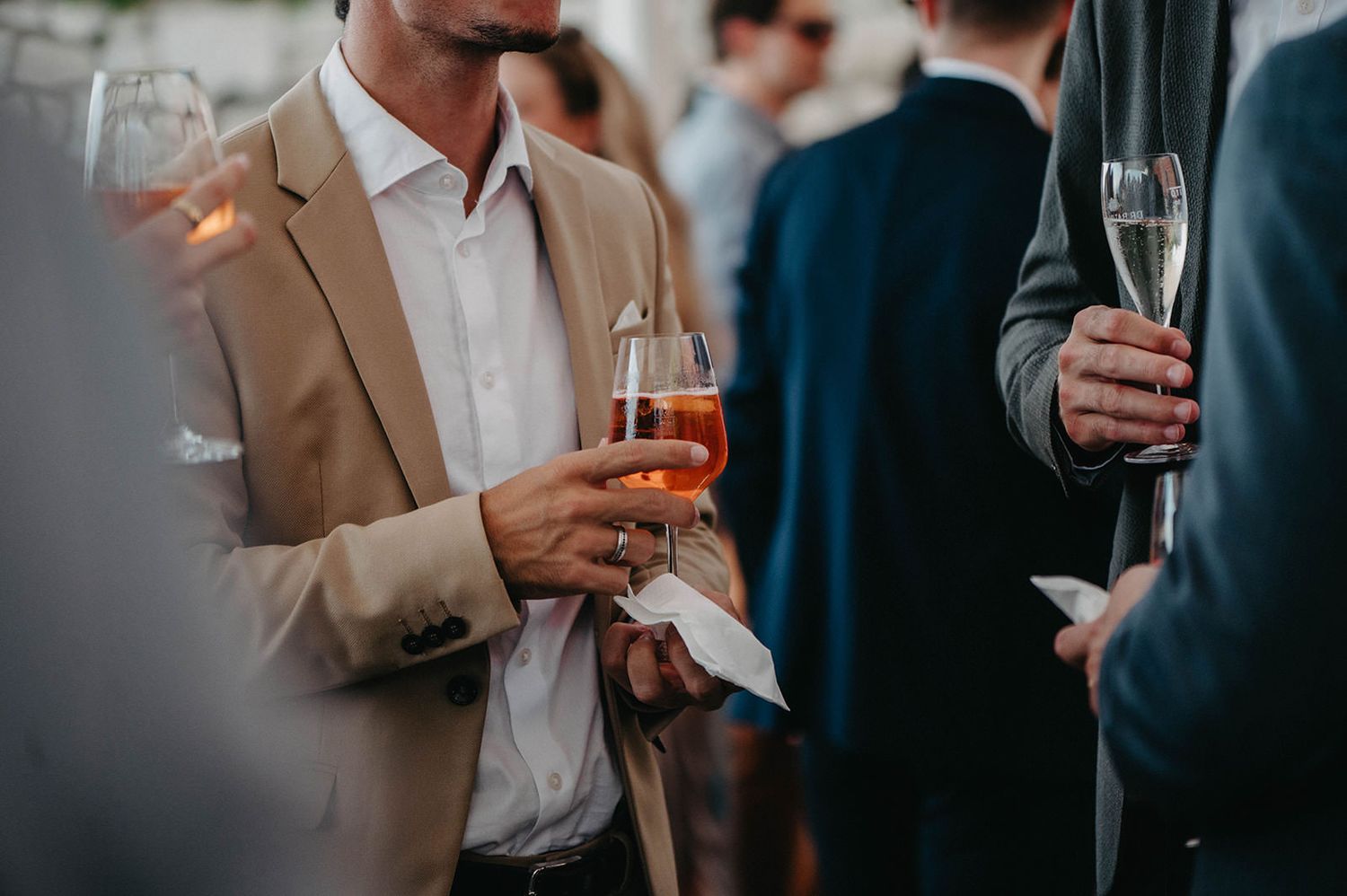 People holding wine and cocktail glasses at an elegant social gathering or party.