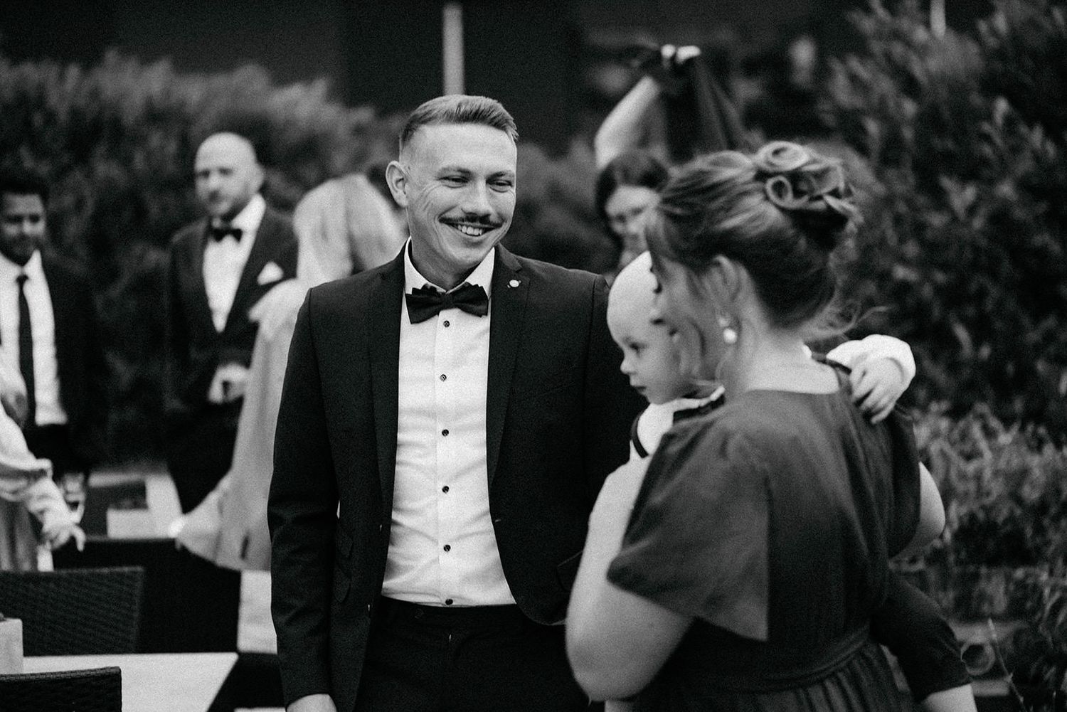Black and white photos show a formal event with people in tuxedos and evening attire mingling at an elegant gathering.