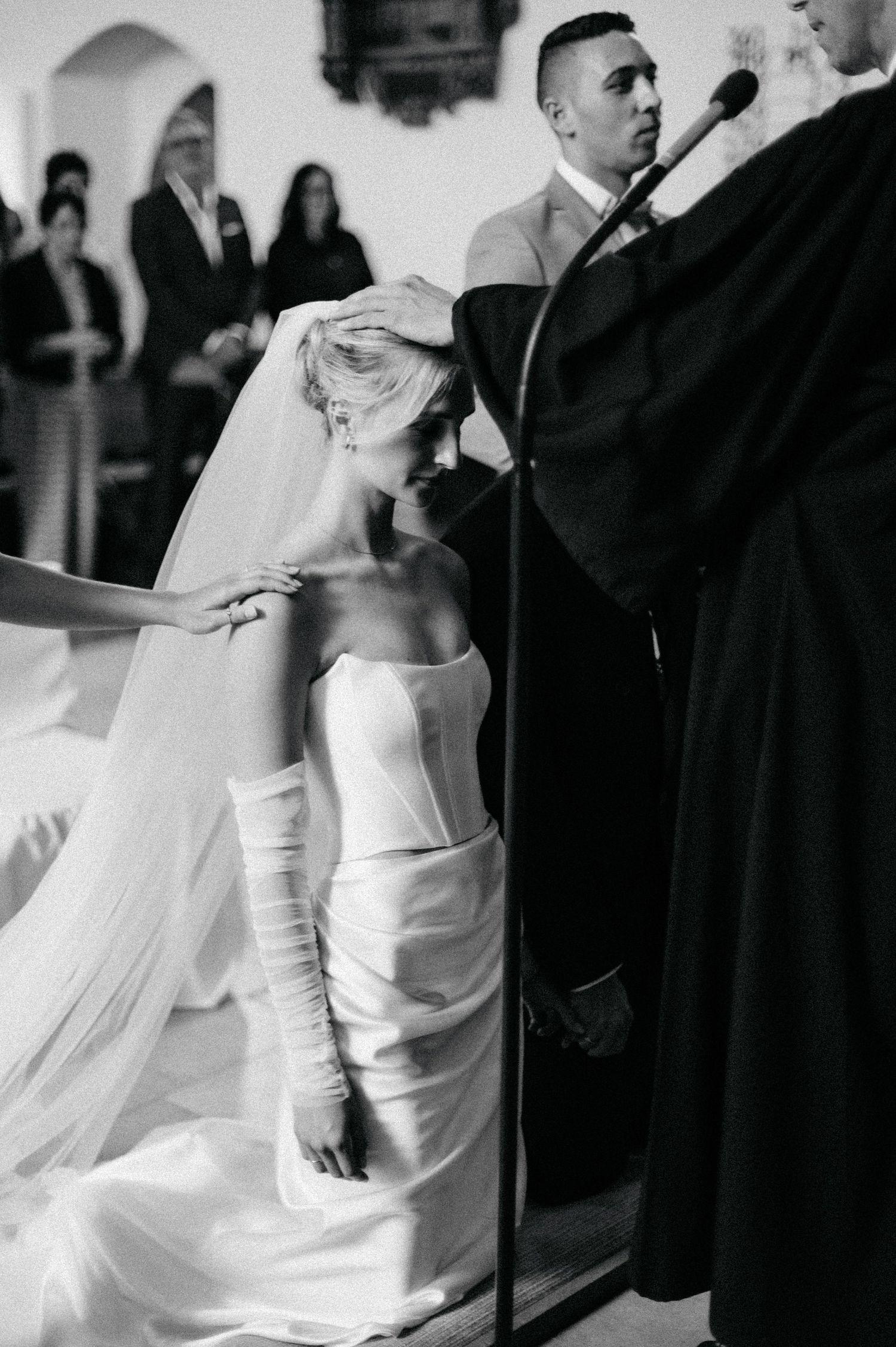 A couple in wedding attire dances together at their reception while guests look on in the background.