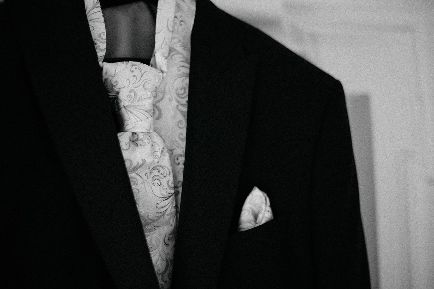 Black and white photograph shows a person in formal attire with a white bow tie and dark jacket.