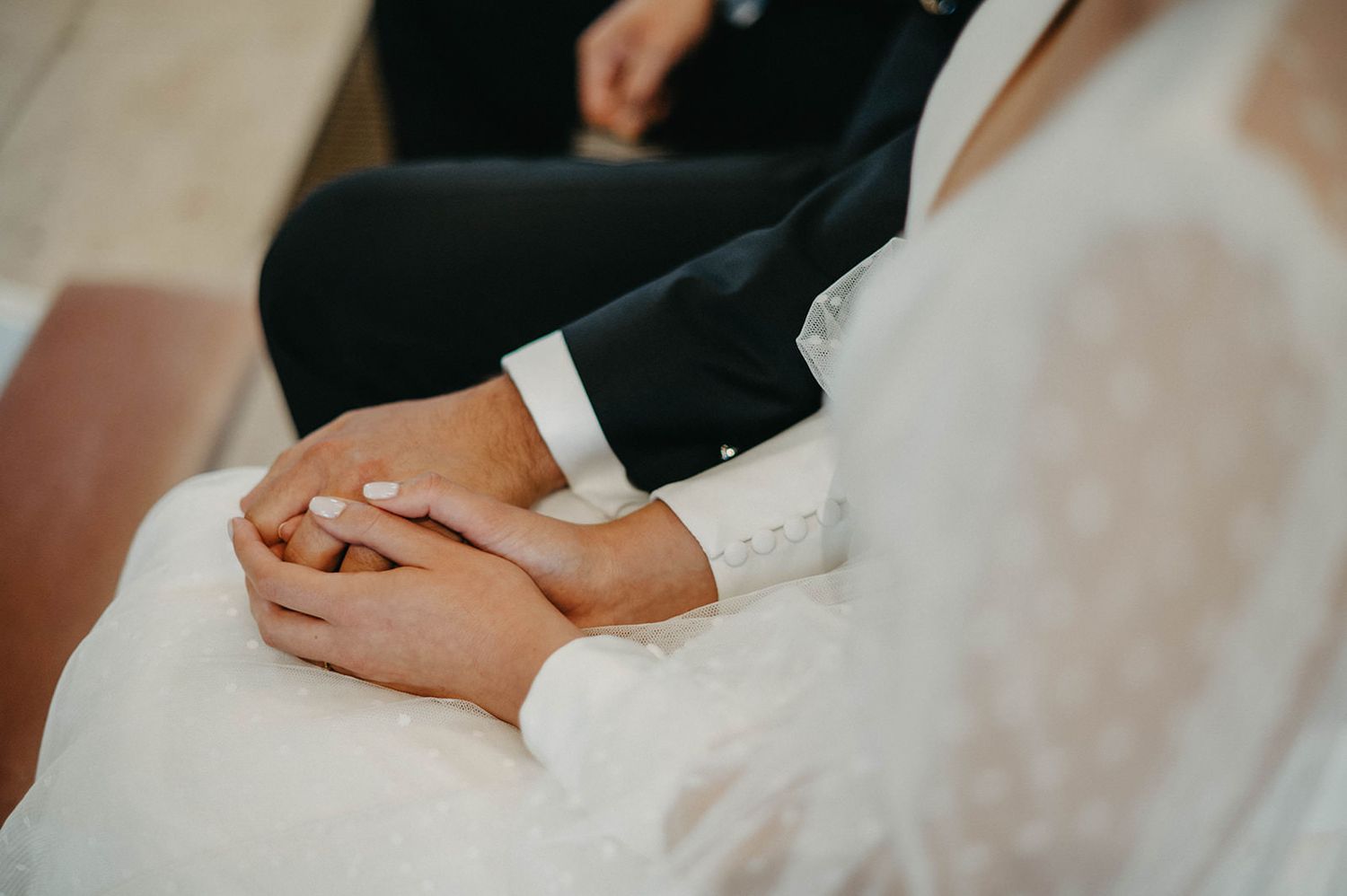 Close-up view of wedding rings being exchanged during a romantic ceremony with hands in elegant attire.