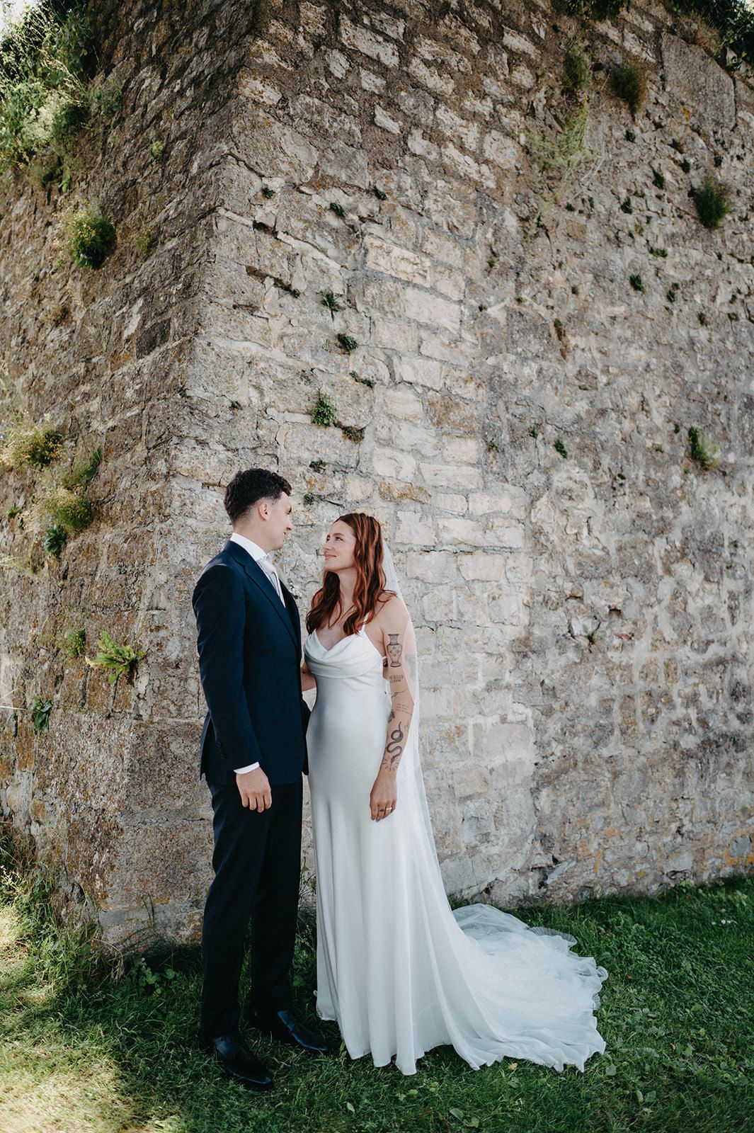 Romantic wedding couple poses against rustic stone wall in a series of intimate moments.
